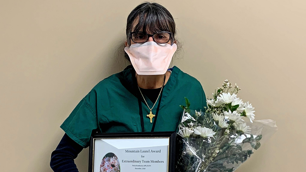 woman wearing a mask while holding a framed award