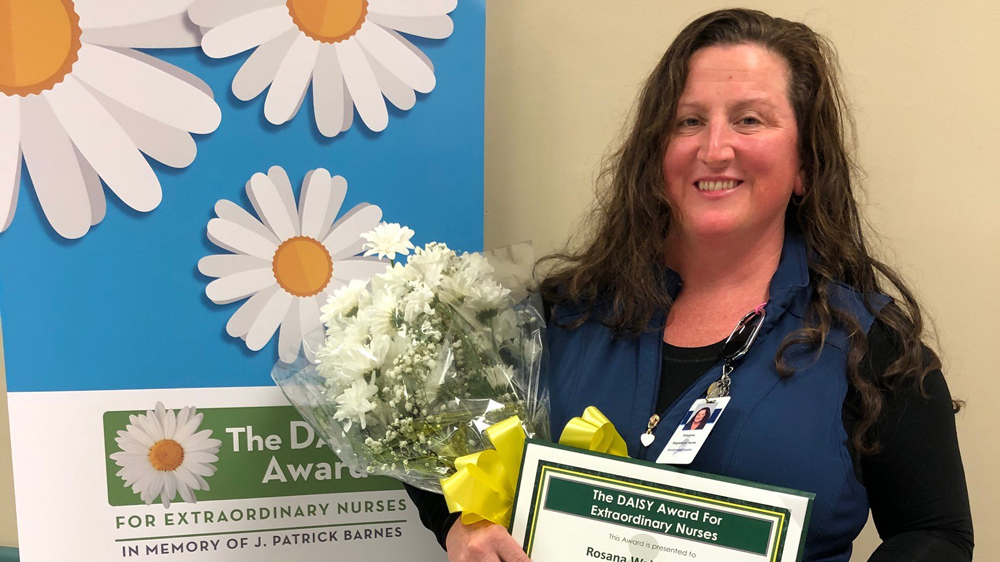 woman holding flowers and award