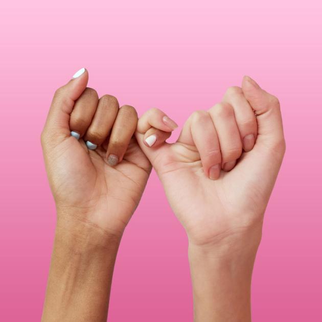 Two hands intertwined at pinky fingers with pink background