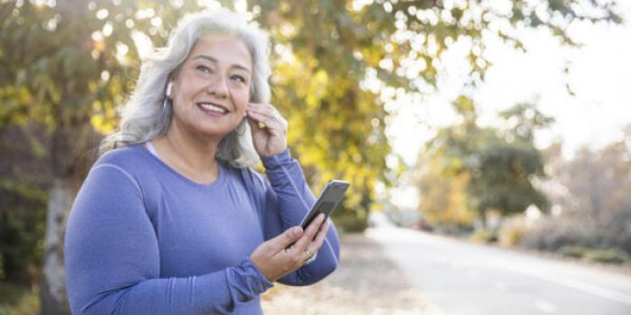 woman smiling while putting on ear plugs outside