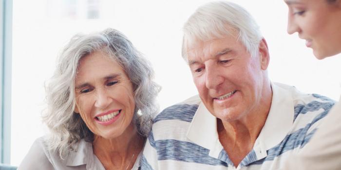 elderly couple and woman seated smiling