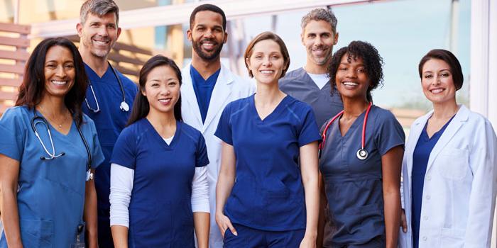 Diverse group of doctors and nurses outside a building.
