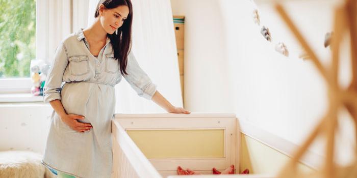 Pregnant woman looking at crib