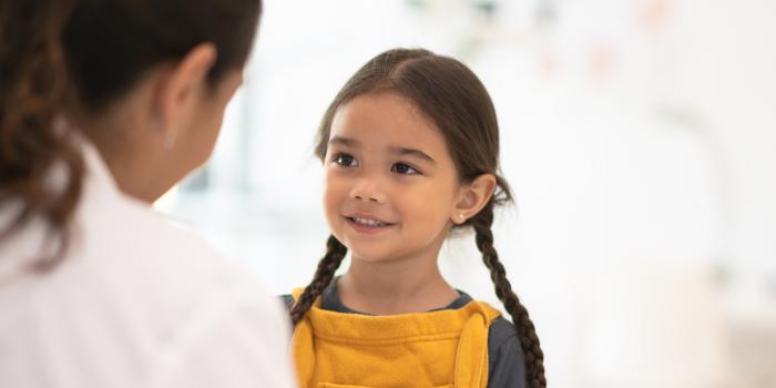 little girl with pig tails smiling at doctor