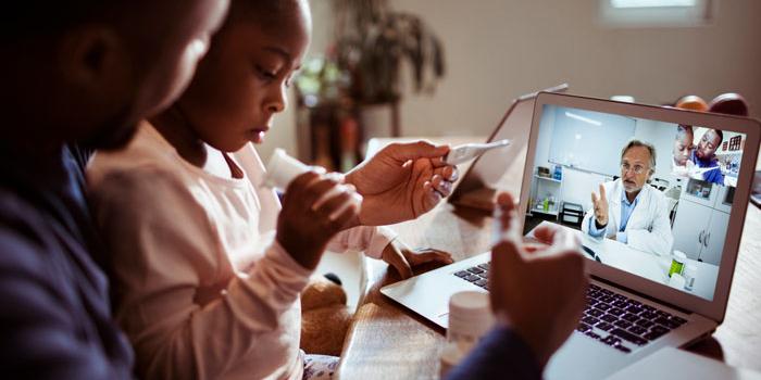 father with daughter and thermometer looking at laptop with doctor on video conference