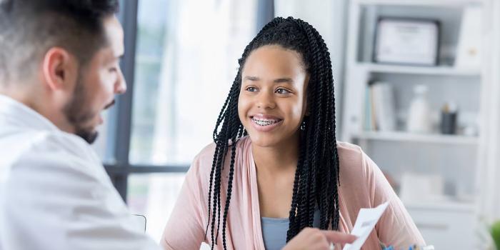 Adolescent girl smiling at her doctor in the consultation room