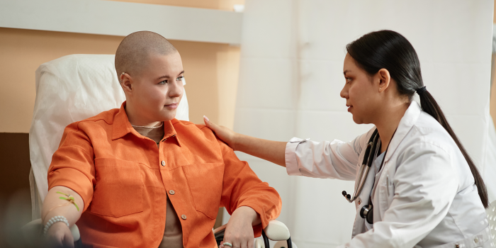 Female cancer patient sitting with female provider touching shoulder