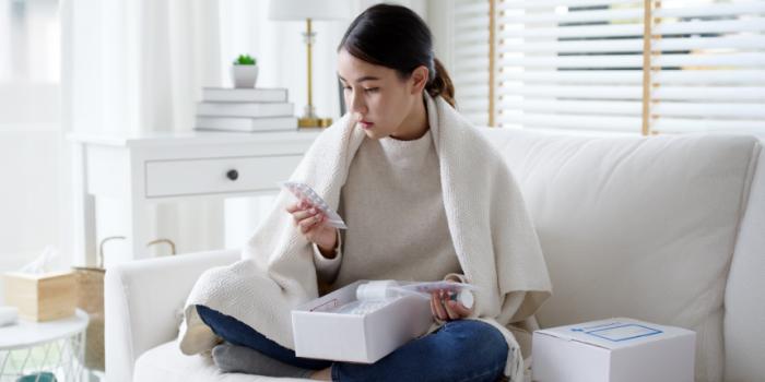 Female patient sits on couch at home, and reviews her prescription delivery.