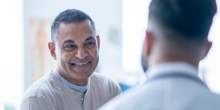 Senior man sitting on an exam table as he meets with doctor