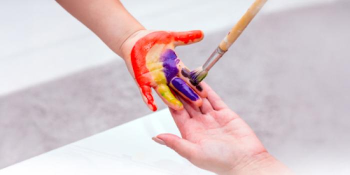 A child's palm is painted by an adult hand at the Child Life center.