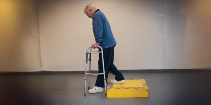 A person places the walker down first, making sure feet are close to edge of the curb. They step down with operated leg first, followed by the non-operated leg.